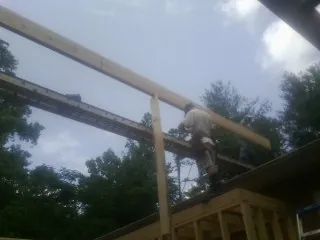 Carpenter setting a ridge beam over a new addition frame — Ice Dam Removal by Roofing Brothers in Shiner