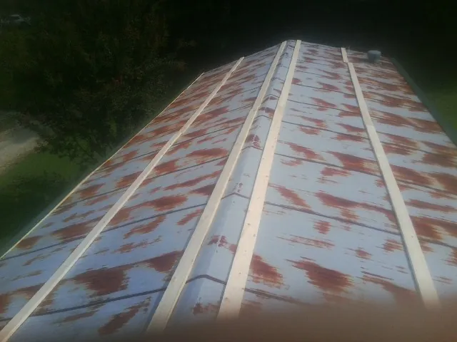 Rusted metal roof panels with new wood purlins before replacement — Storm Damage Roof Repair in Shiner by Roofing Brothers