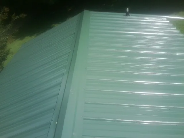New green metal panels meeting at the ridge of a roof — Flat Roof Repair work by our crew in Shiner