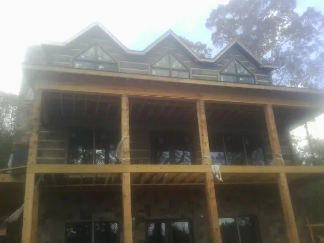 Dormers and porch framing on a large log home under construction — Roof Coating work by our crew in Shiner