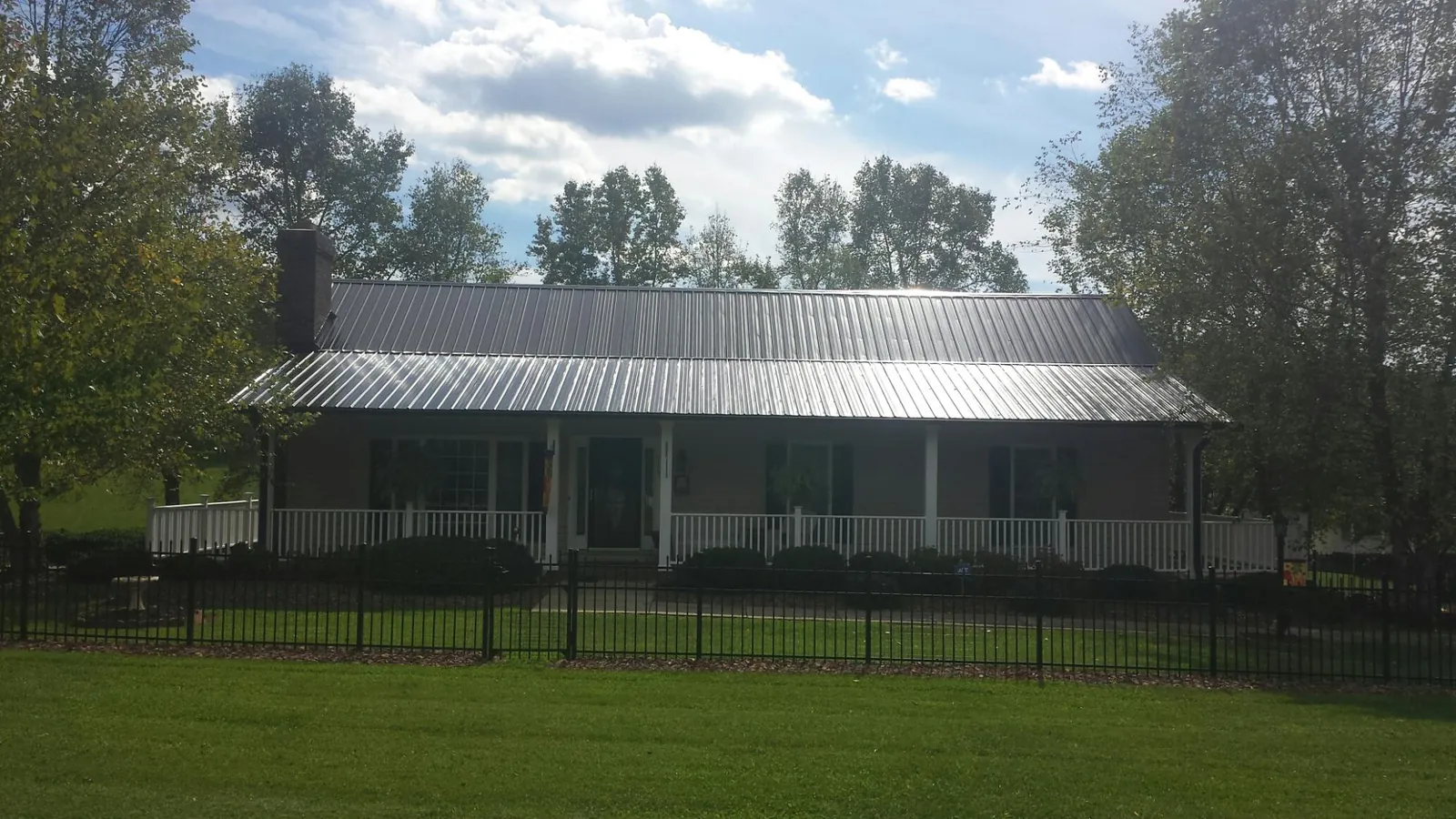 Gray metal roof on a brick ranch with a full width front porch — Gutter Guard Installation work by our crew in Shiner