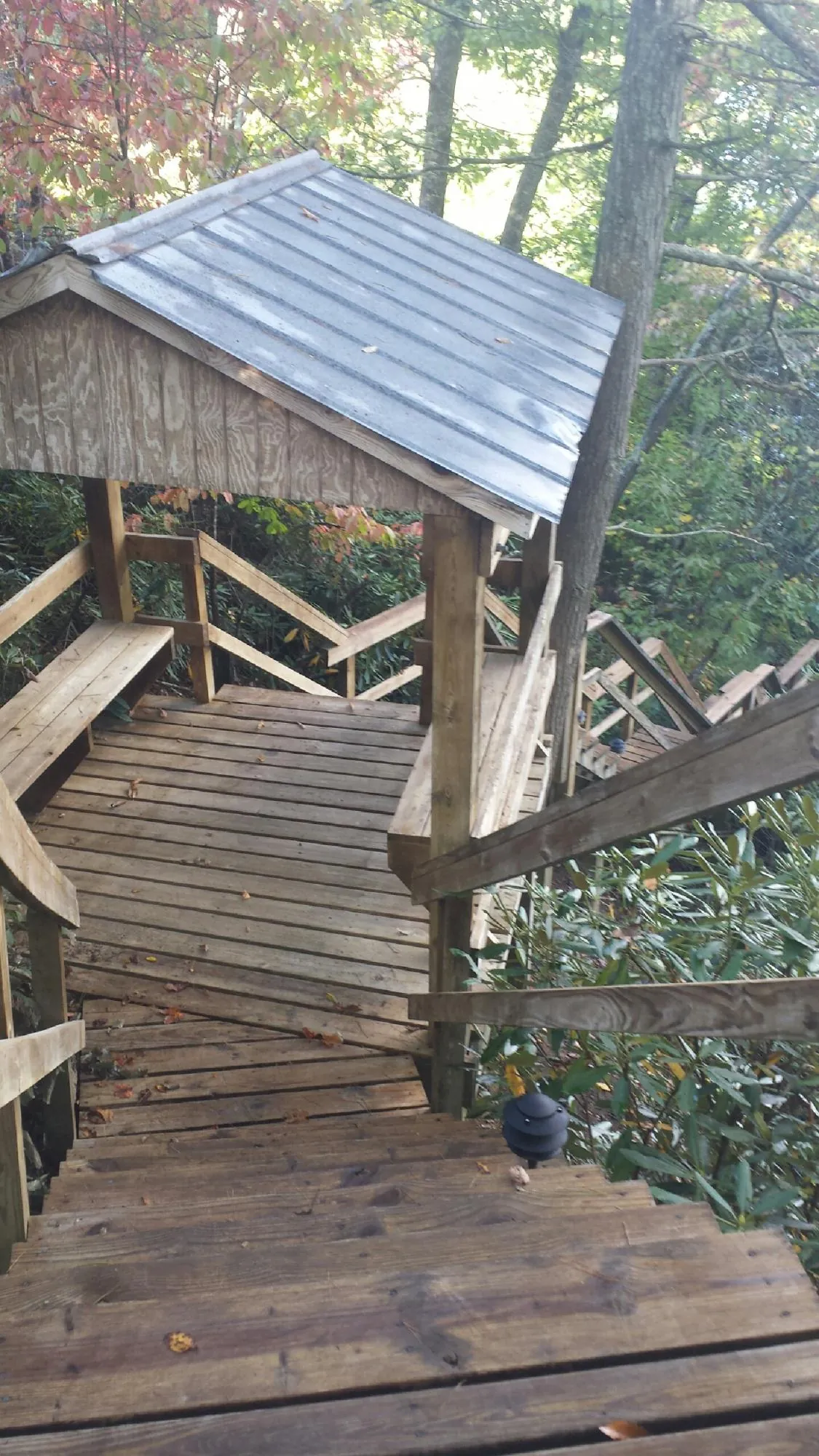 Metal roofed shelter over wooden steps on a wooded walkway — Skylight Repair & Installation work by our crew in Shiner